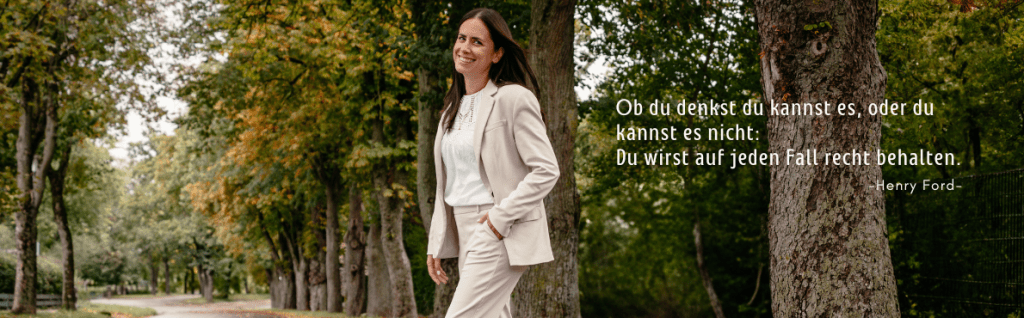 Eine Frau in einem hellen Anzug steht in einem parkähnlichen Umfeld mit Bäumen, während sie lächelt und eine inspirierende Zitat von Henry Ford zeigt.